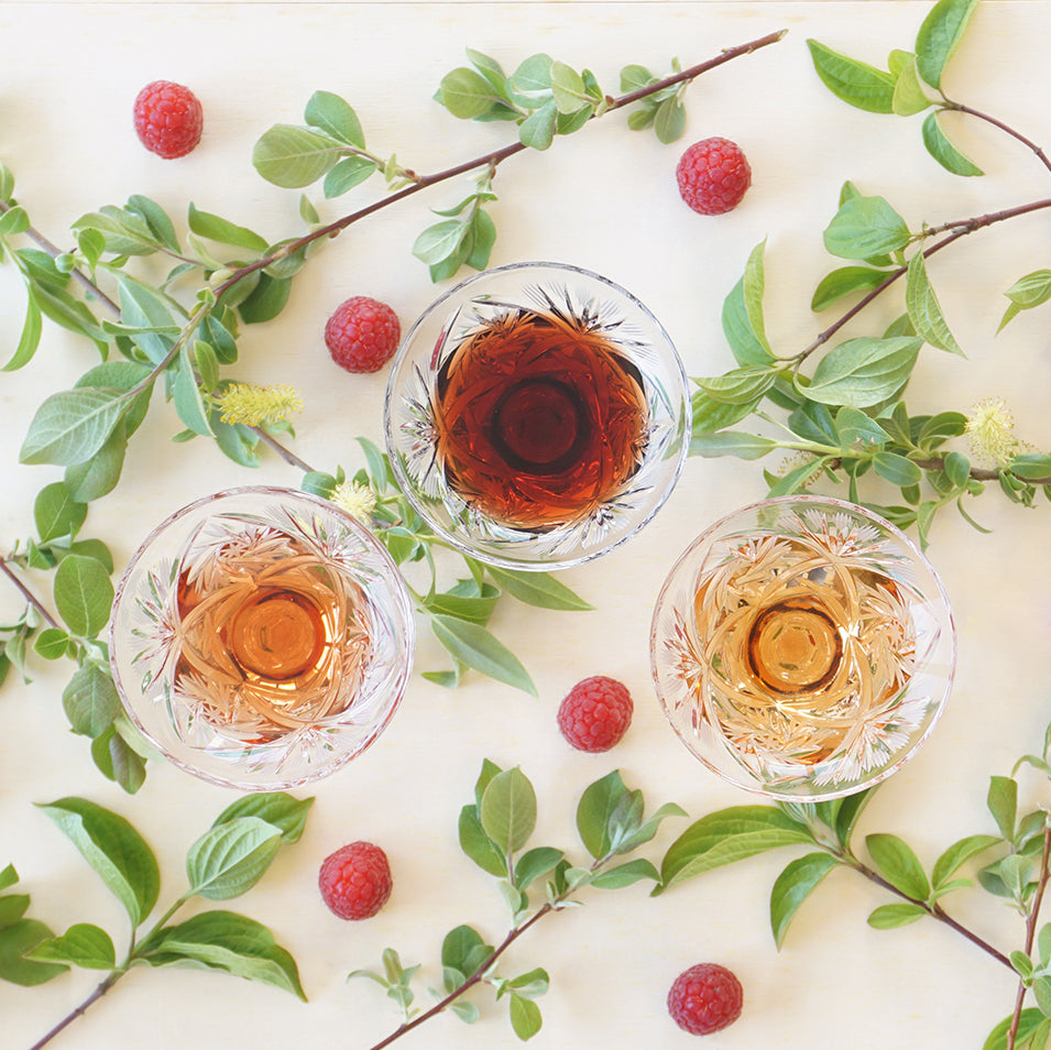 3 Fruchtessige in Aperitif Gläsern mit einer Blumendekoration