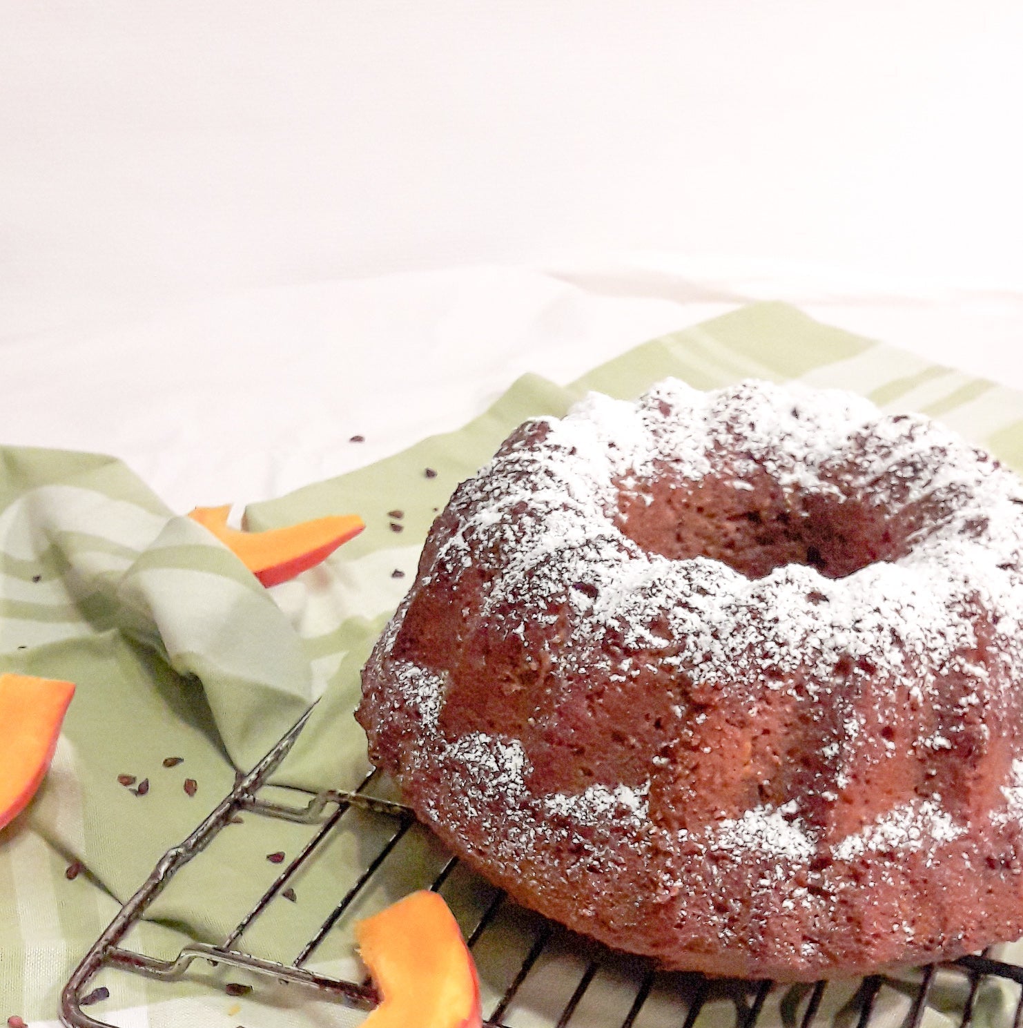 ein brauner Kürbis-Napfkuchen angerichtet mit Kürbisstreifen auf einem Gitterrost