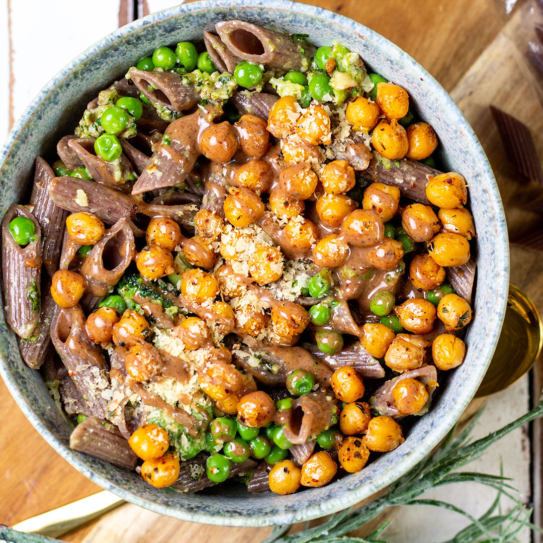 Eine Schale gefüllt mit einem gekochten Gericht aus Traubenkern Penne Rigate, Kichererbsen und grünen Erbsen.