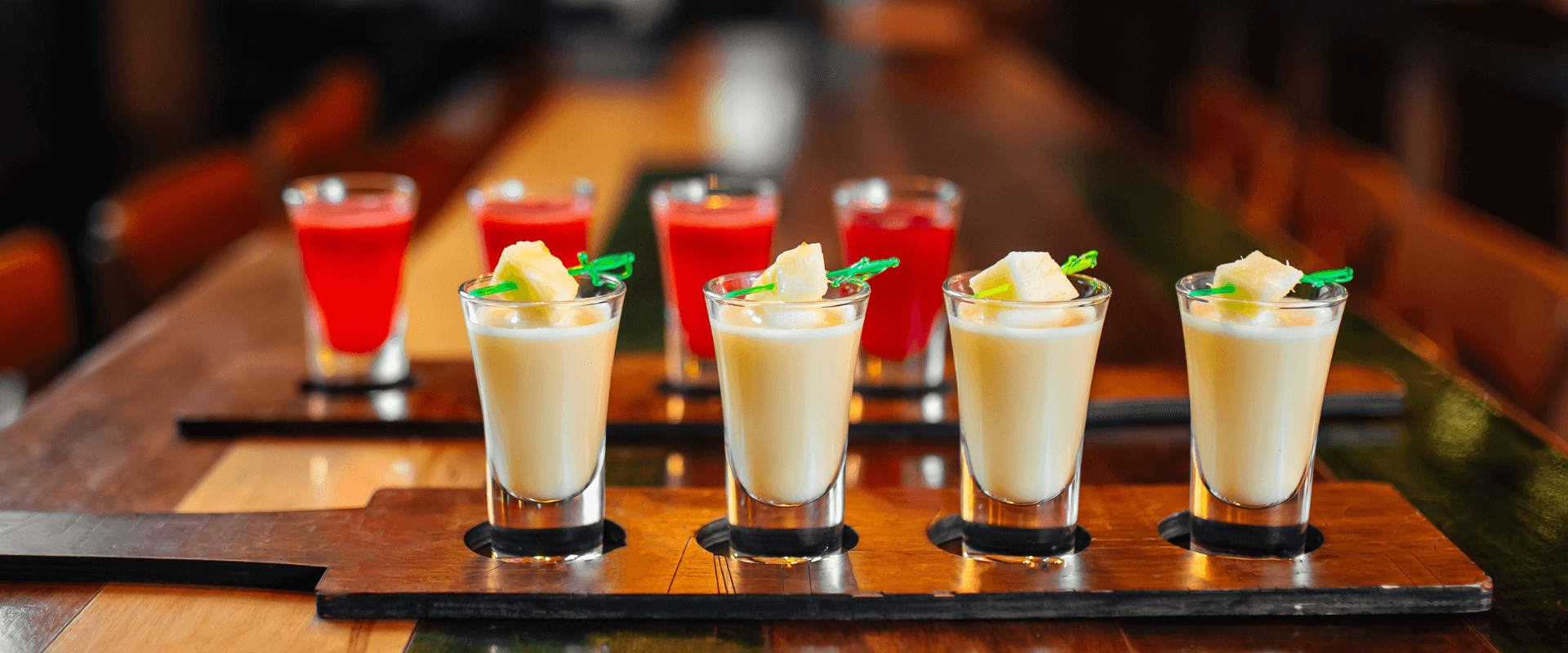 Kleine Likörgläser mit verschiedenen Likören stehen auf einem dunklen Tisch.