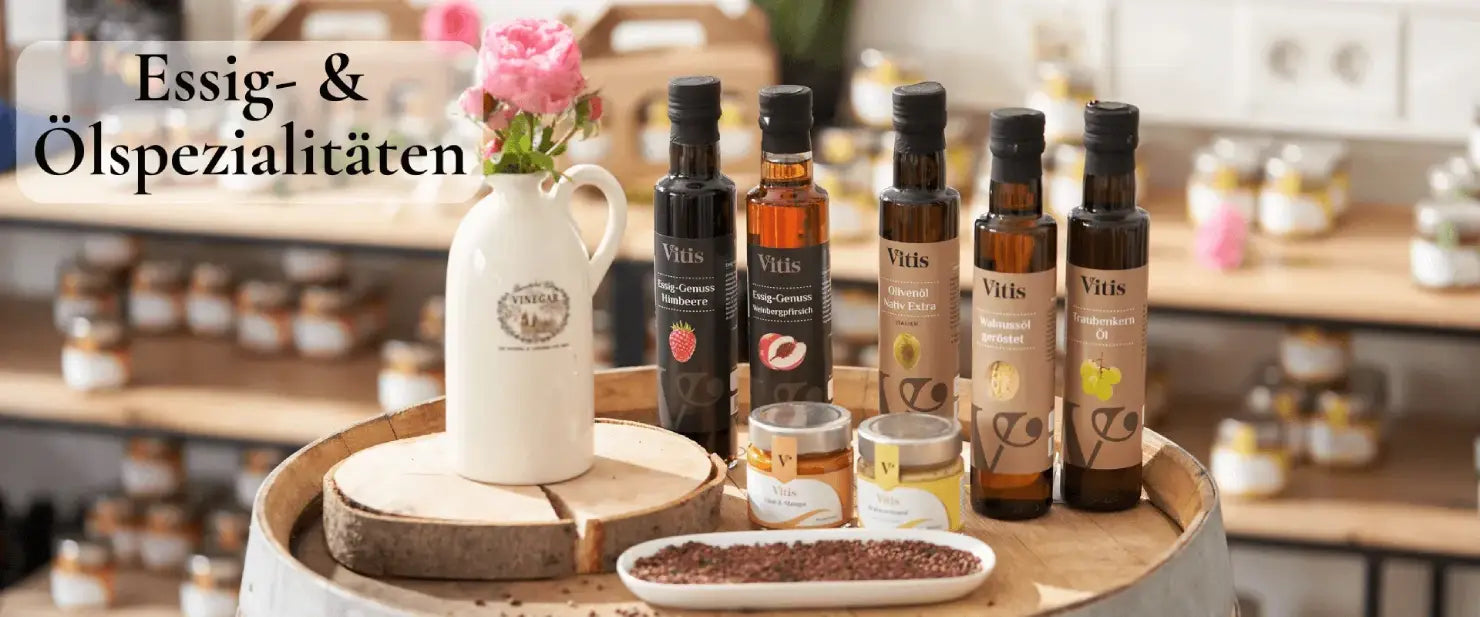 Verschiedene Feinkostprodukte und kaltgepresste Ölspezialitäten der Firma Vitis Traubenkern GmbH auf einem Weinfass dekoriert.
