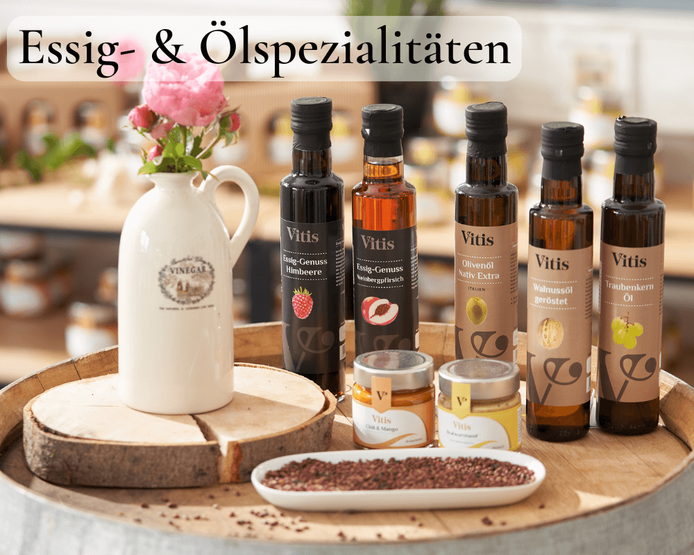 Verschiedene Feinkostprodukte und kaltgepresste Ölspezialitäten der Firma Vitis Traubenkern GmbH auf einem Weinfass dekoriert.