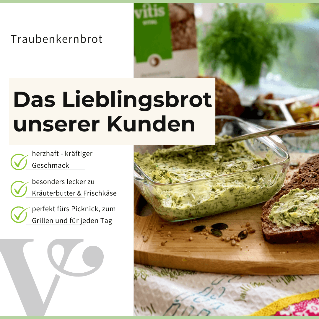 Eine Traubenkernbrot von Vitis, mit Kräuterbutter bestrichen, liegt auf einem Holzbrett.