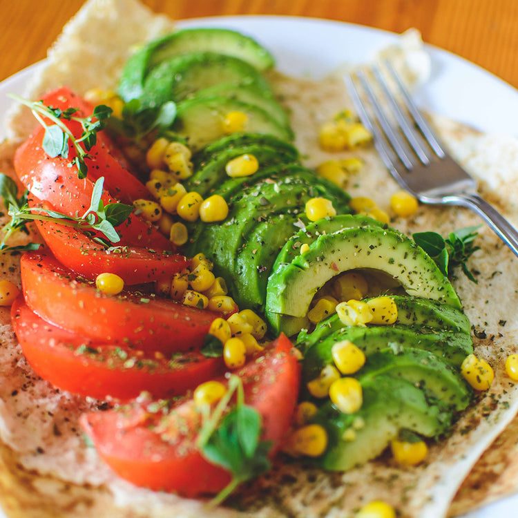 Ein Salat aus Tomaten, Avocados und Mais auf einem Wrap.